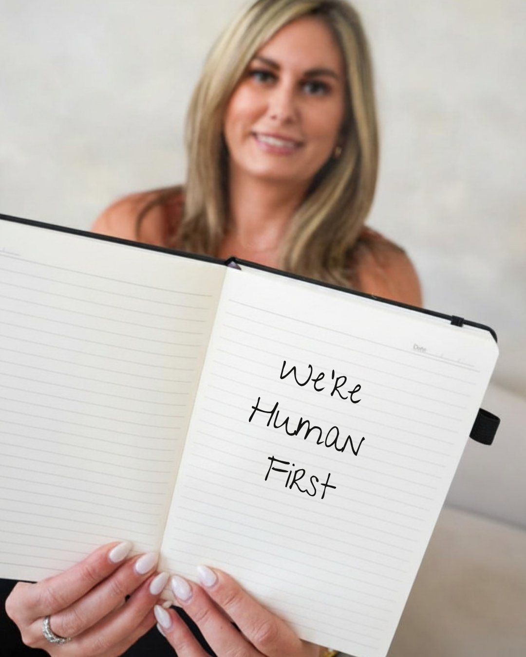 Nicole Meyer holding an open notebook with the words We're Human First handwritten inside
